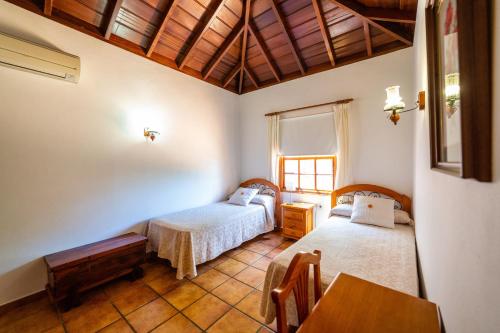 a bedroom with two beds and a table in it at One bedroom villa with sea view private pool and furnished garden at Tijarafe in Tijarafe
