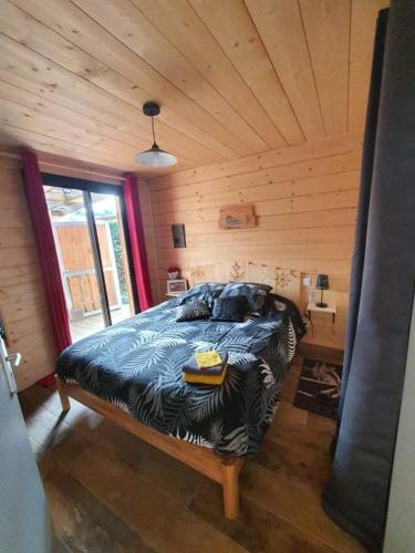 une chambre avec un lit dans une cabane en bois dans l'établissement LA CABANE Cassy, à Lanton