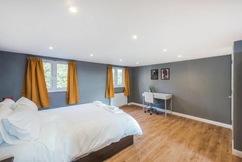 Schlafzimmer mit einem großen weißen Bett und einem Schreibtisch in der Unterkunft Spacious 4 bed house near Greenwich in London