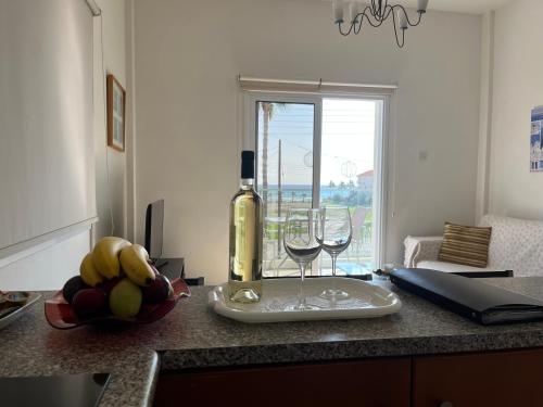 Una botella de vino y dos vasos en una barra de cocina en Themis Apartments en Lárnaca