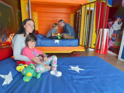 a woman and a little girl sitting on a bed in a room at Gardaland Hotel in Castelnuovo del Garda