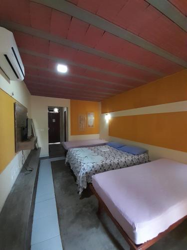 a room with three beds and a tv in it at Pousada Nosso Recanto Camocim in Camocim