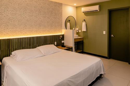 a bedroom with a large white bed and a mirror at Hotel Principe in Tuluá