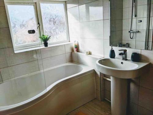Handsworth的住宿－Hidden Gem !Stunning 3 bedroom home in Sheffield，带浴缸、水槽和窗户的浴室