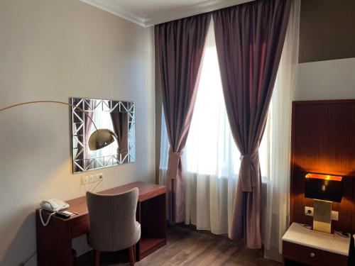 a room with a desk and a window with a chair at Ramada by Wyndham Plovdiv Trimontium in Plovdiv