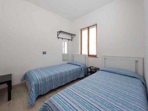 Holiday home in Lignano 21664 في لينانو سابيادورو: سريرين في غرفة بجدران بيضاء ونوافذ