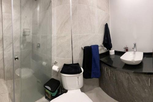 y baño con aseo, lavabo y ducha. en Dpo 2 dorm(parqueadero wifi Netflix)vista pan. UIO, en Quito
