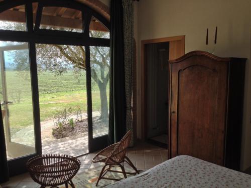 a bedroom with a bed and chairs and a window at Agriturismo Borgo Laurice in Torgiano
