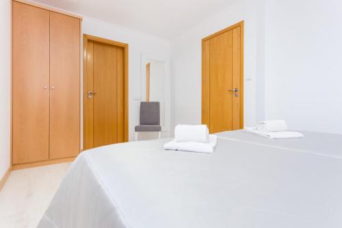 a white bedroom with a large white bed with wooden cabinets at T3 Bliss by Seewest in Albardeira