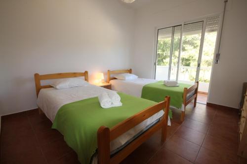 a bedroom with two beds with green sheets and a window at T3 Casa dos Arcos by Seewest in Salema