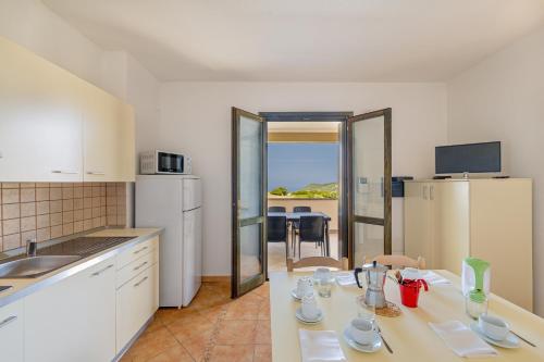 cocina con mesa, sillas y encimera en Residenza Le Farfalle, en Tergu