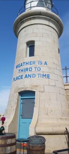 a lighthouse with a sign that says weather is a time to place and time at Beautifully appointed, period seaside apartment in Folkestone