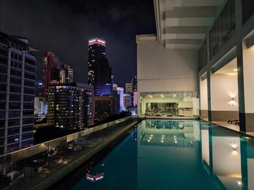 a swimming pool with a city skyline at night at One Bukit Ceylon KLCC in Kuala Lumpur