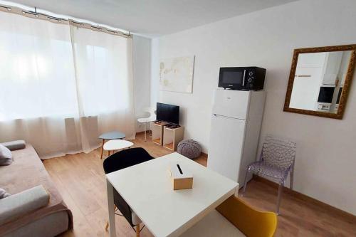 una pequeña sala de estar con una mesa blanca y sillas en Appartements cosy BELFORT en Belfort