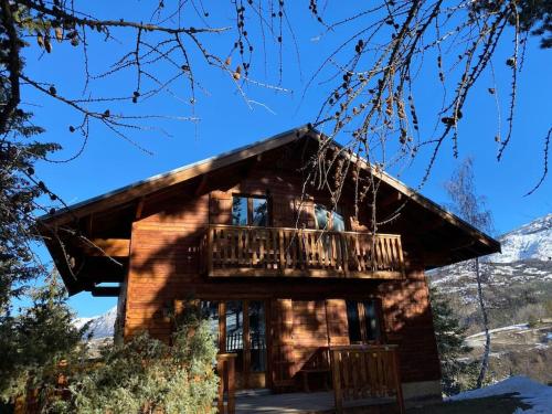 a log cabin with a balcony in the mountains at Le refuge, chalet au pied des pistes au Sauze in Enchastrayes