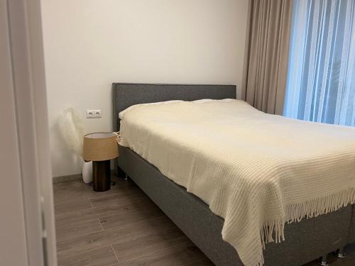a bedroom with a bed with a white blanket at Jūros kelias in Palanga