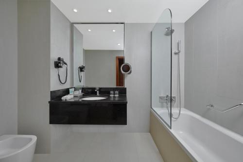 a bathroom with a tub and a sink and a mirror at Holiday Inn Tabuk by IHG in Tabuk