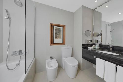 a white bathroom with a toilet and a sink at Holiday Inn Tabuk by IHG in Tabuk