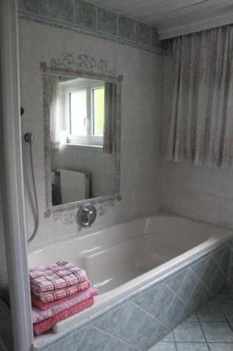 a bathroom with a tub with a mirror and pink towels at Ferienwohnung Stuibenfall in Jerzens