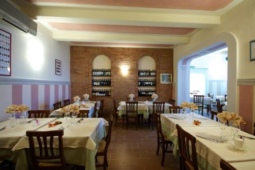 una sala da pranzo con tavoli con tovaglie bianche di Affittacamere Dal Falco a Pienza