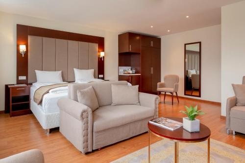um quarto de hotel com uma cama, um sofá e uma mesa em Palast Hotel em Hürth