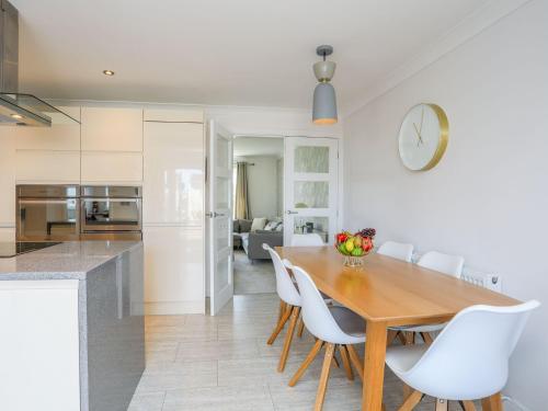 a kitchen and dining room with a wooden table and white chairs at Brynelian in Moelfre