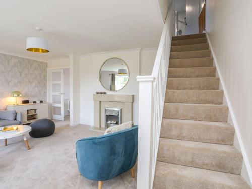 a living room with a staircase and a blue chair at Brynelian in Moelfre