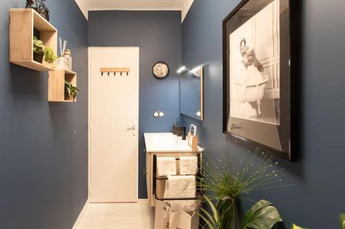 La salle de bains est pourvue d'un lavabo et d'une horloge murale. dans l'établissement C5 - 2 BDR Blvd Carnot - 10 min Palais - AC & Terrace Sea View, à Cannes