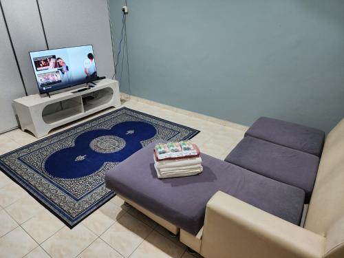 a living room with a purple couch and a tv at Homestay DeUmmah House in Cukai
