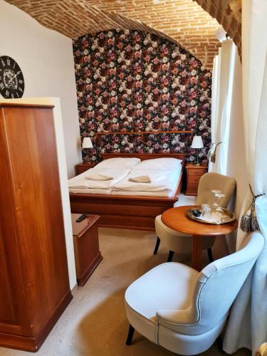 a bedroom with a bed and a table and a chair at Penzión pod kláštorom in Pezinok