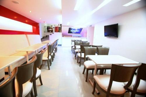 a dining room with tables and chairs and a tv at AW Hotel Ariston in Bogotá