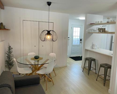 a dining room and kitchen with a glass table and chairs at Condo En Quatre Temps in Beaupré