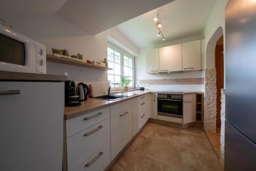 a kitchen with white cabinets and a stove top oven at Apartment Tinney in Kössen