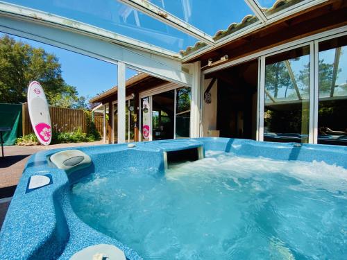 a swimming pool with a surfboard next to a house at Villa Patio + jacuzzi, FREE Surf+Body+Sup in Capbreton