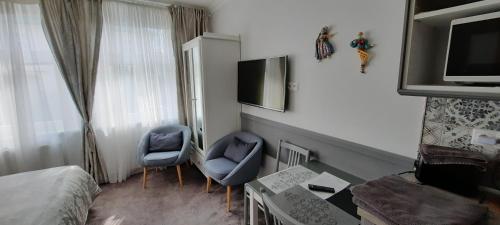 a hotel room with two blue chairs and a television at Villa Shafaly in Mariánské Lázně