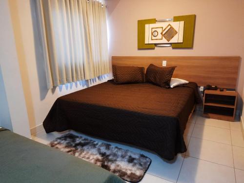 Matinada Palace Hotel في Paraguaçu: غرفة نوم مع سرير مع اللوح الأمامي الخشبي