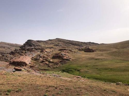 a hillside with rocks and grass in a field at Gite Oukaimeden in Oukkainrdem