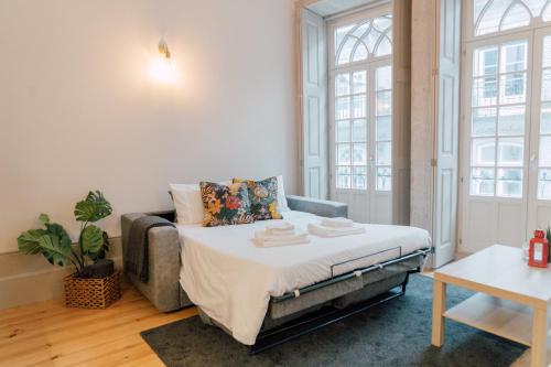 ein Schlafzimmer mit einem Bett, einem Sofa und Fenstern in der Unterkunft Casa Burguesa Rua do Almada - Porto city center in Porto