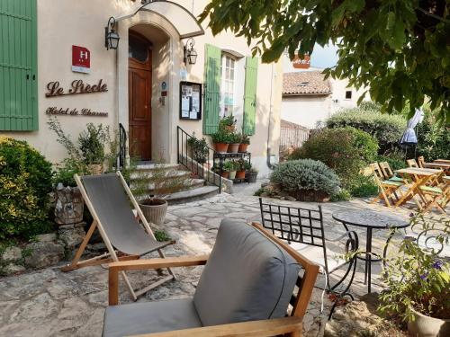 eine Terrasse mit Stühlen und einem Tisch vor einem Gebäude in der Unterkunft Hôtel Le Siècle in Mazan