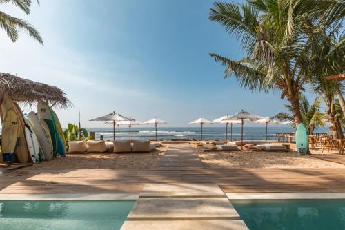 a resort with a pool and a beach with umbrellas at The Hotel in Ahangama
