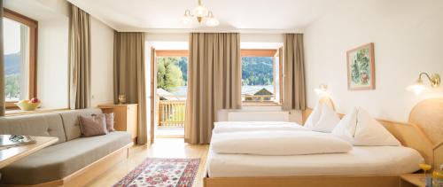 ヴァイセンゼーにあるFerienhof Neusacher Moserのベッド2台とソファが備わるホテルルームです。