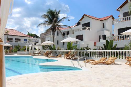 un complejo con una piscina con sillas y sombrillas en VAIA HOTELES, en Coveñas