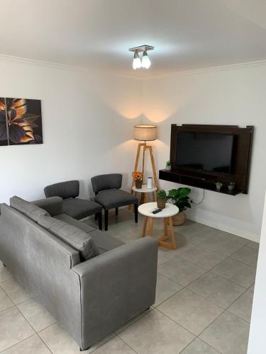 ein Wohnzimmer mit einem Sofa und einem Flachbild-TV in der Unterkunft Lumiere Apartments - Confortable Departamento en Complejo Residencial in Mendoza