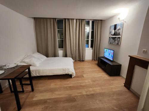 Schlafzimmer mit einem Bett, einem Tisch und einem TV in der Unterkunft Studio cozy centre ville rdc in Bar-le-Duc