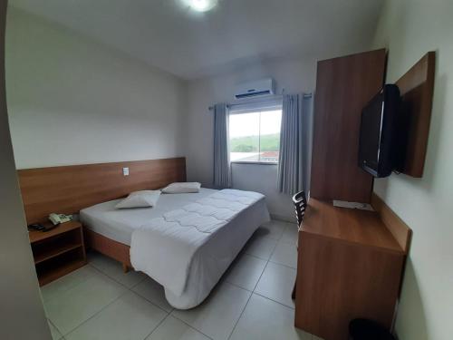 a hotel room with a bed and a television at Matinada Palace Hotel in Paraguaçu