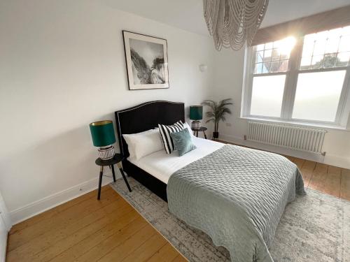 a bedroom with a bed and two lamps and a window at 1 Bed / 1 Sofa Bed 'Scandi' Style Ground Floor Apartment in Yeovil