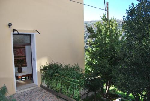 a white building with a gate and a tree at B&B Baddesalighes in Bolotana