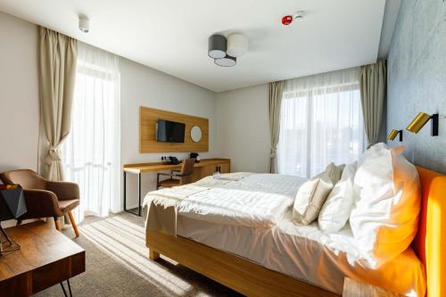 a bedroom with a bed and a desk and a tv at Hotel Historia Malomkert in Veszprém