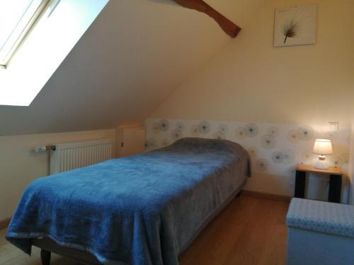 a bedroom with a blue bed in a attic at gite l'opale in Lailly-en-Val