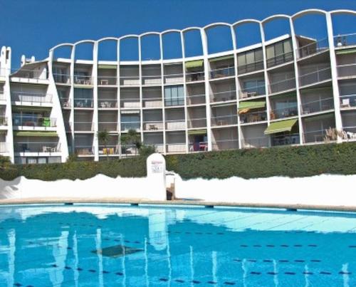 un hôtel avec une piscine devant un immeuble dans l'établissement *Les Dunes, 50 m des plages, clim, Netflix,4 pers*, à La Grande Motte